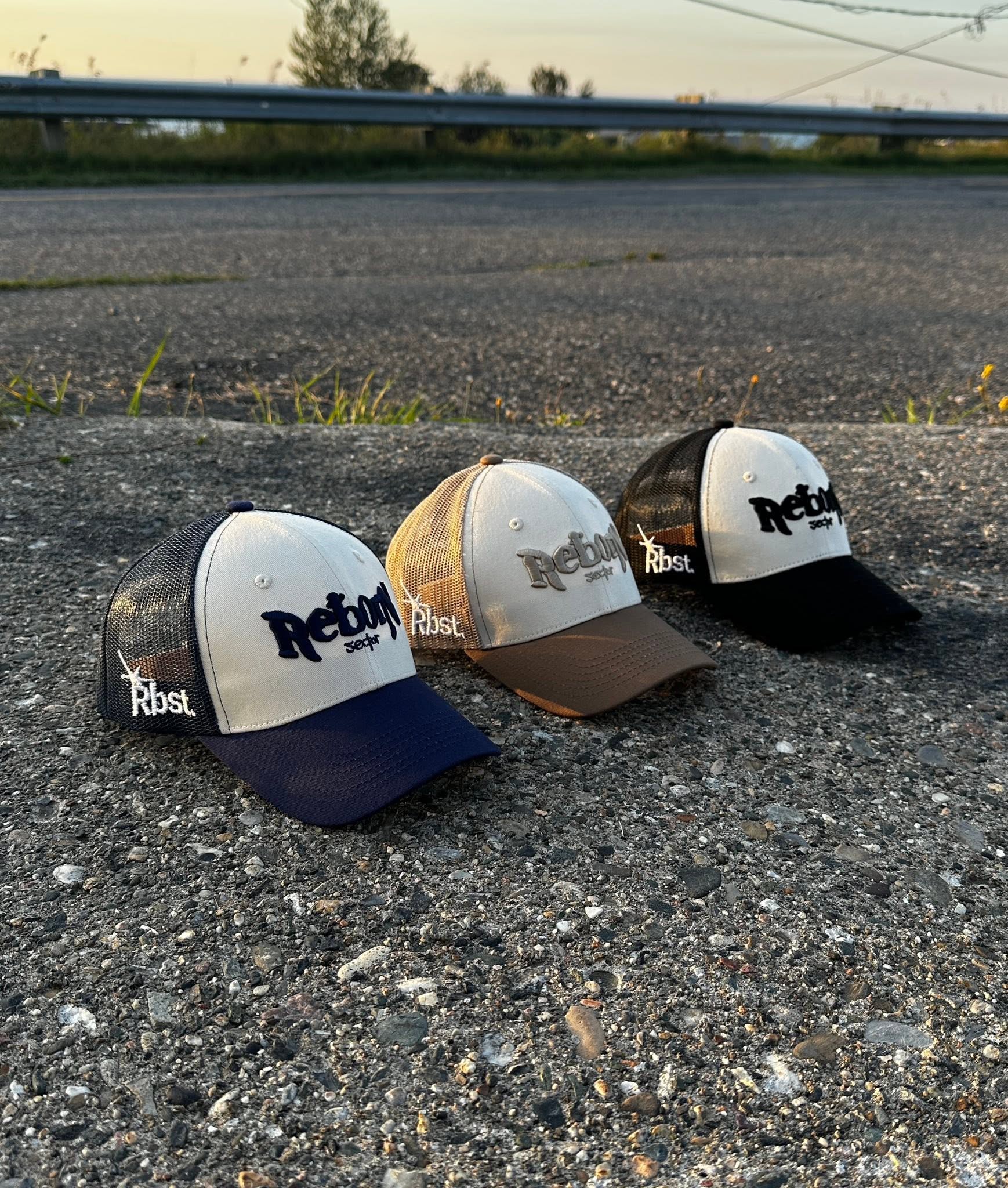 Trois casquettes Reborn Sector en bleu, brun et noir.