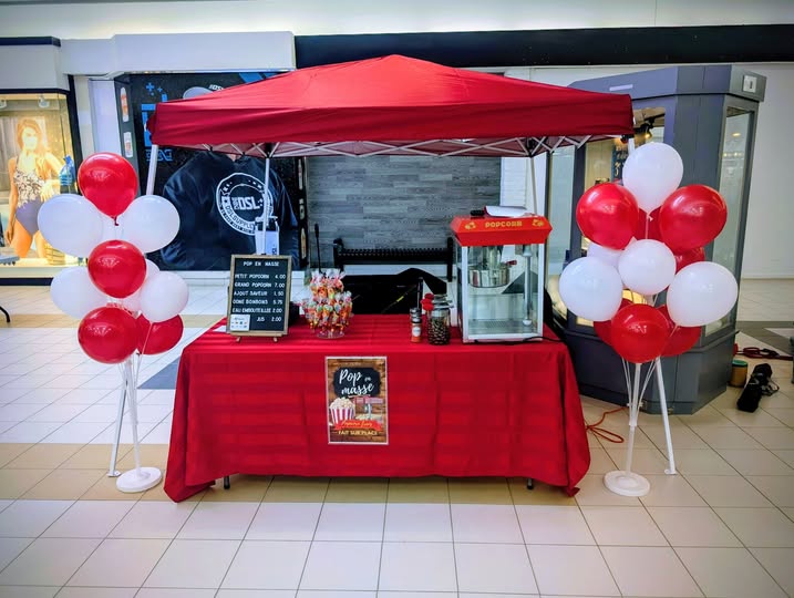Kiosque Pop en Masse sous un chapiteau rouge avec des ballons rouges et blancs