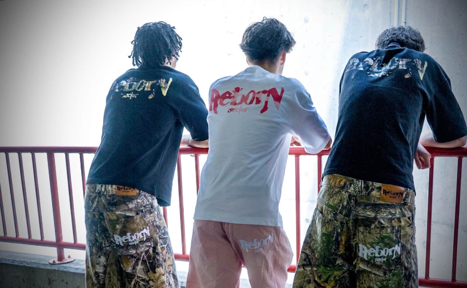 Trois personnes portant des t-shirts et des pantalons Reborn Sector.