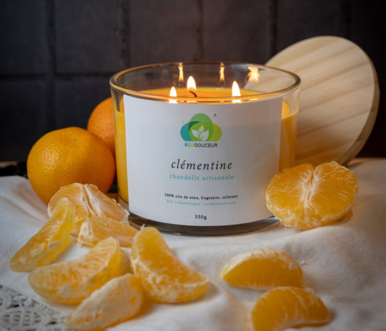 Chandelle artisanale Ecodouceur à la clémentine allumée, entourée de quartiers de clémentine