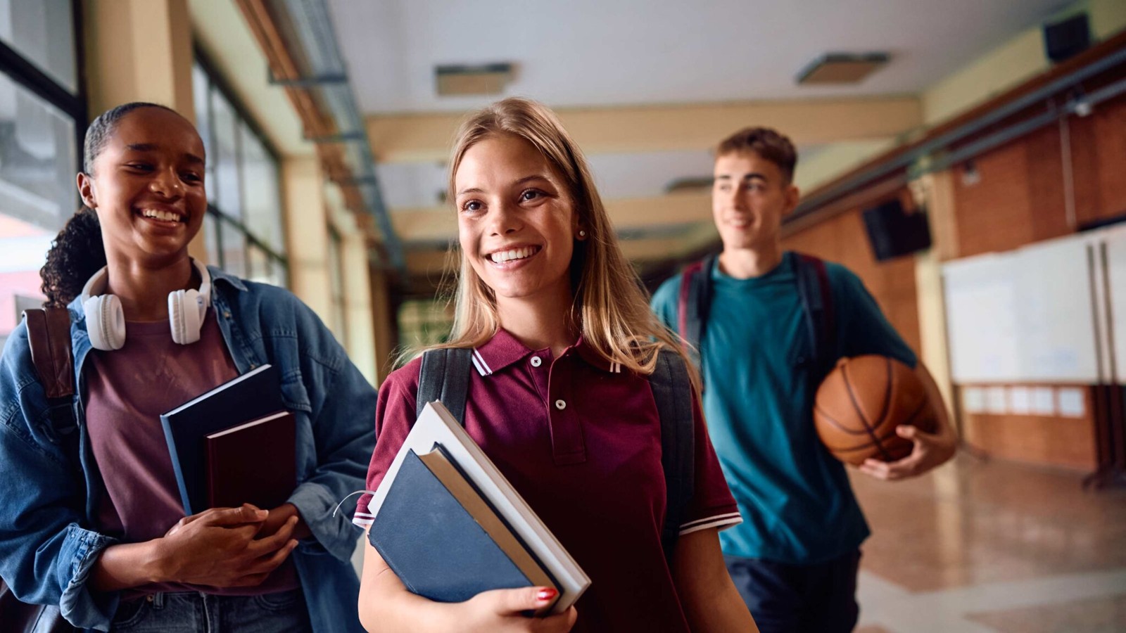 Trois étudiants souriants dans un établissement scolaire