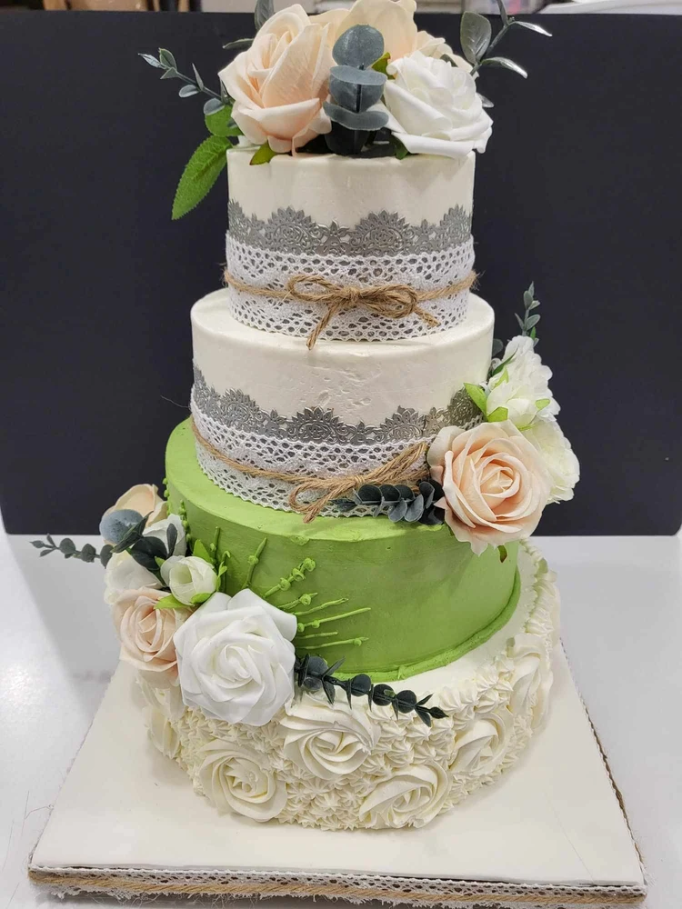 Gâteau de mariage à étages décoré de fleurs, de dentelle et de rubans
