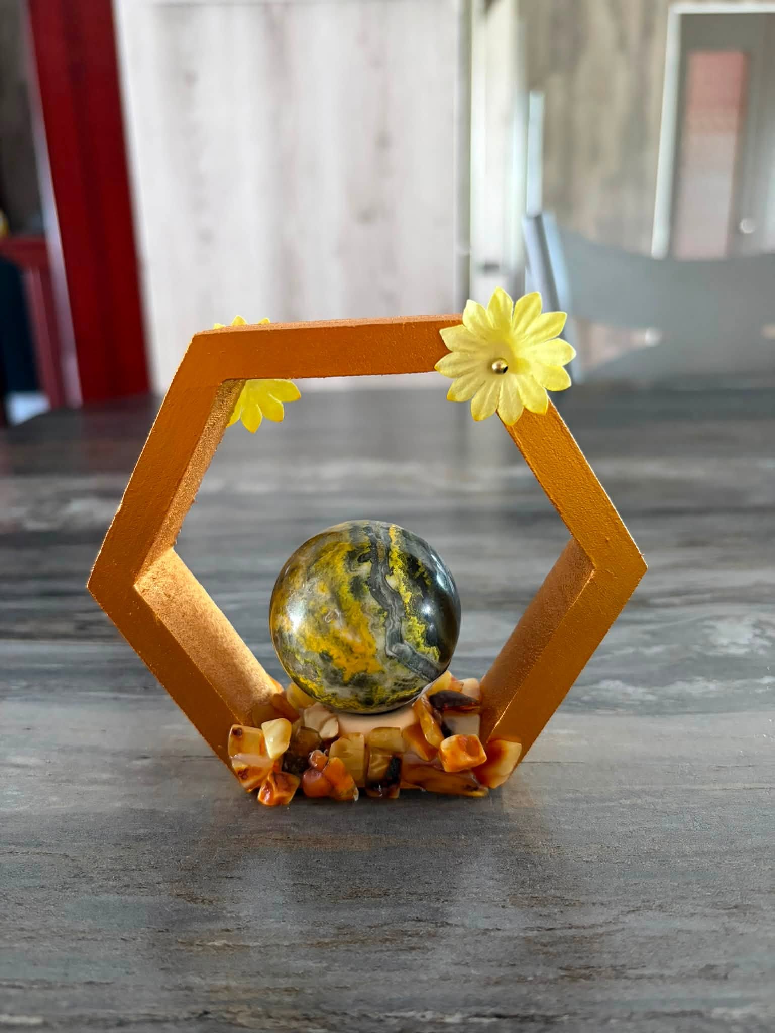 Composition décorative de C. Dragonia dans un cadre hexagonal doré avec fleurs jaunes